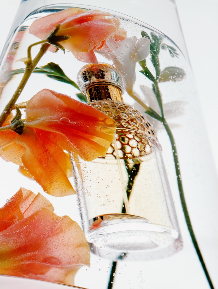 Flacon de parfum Guerlain avec fleurs décoratives. Par Edouard Sicot, photographe lifestyle.